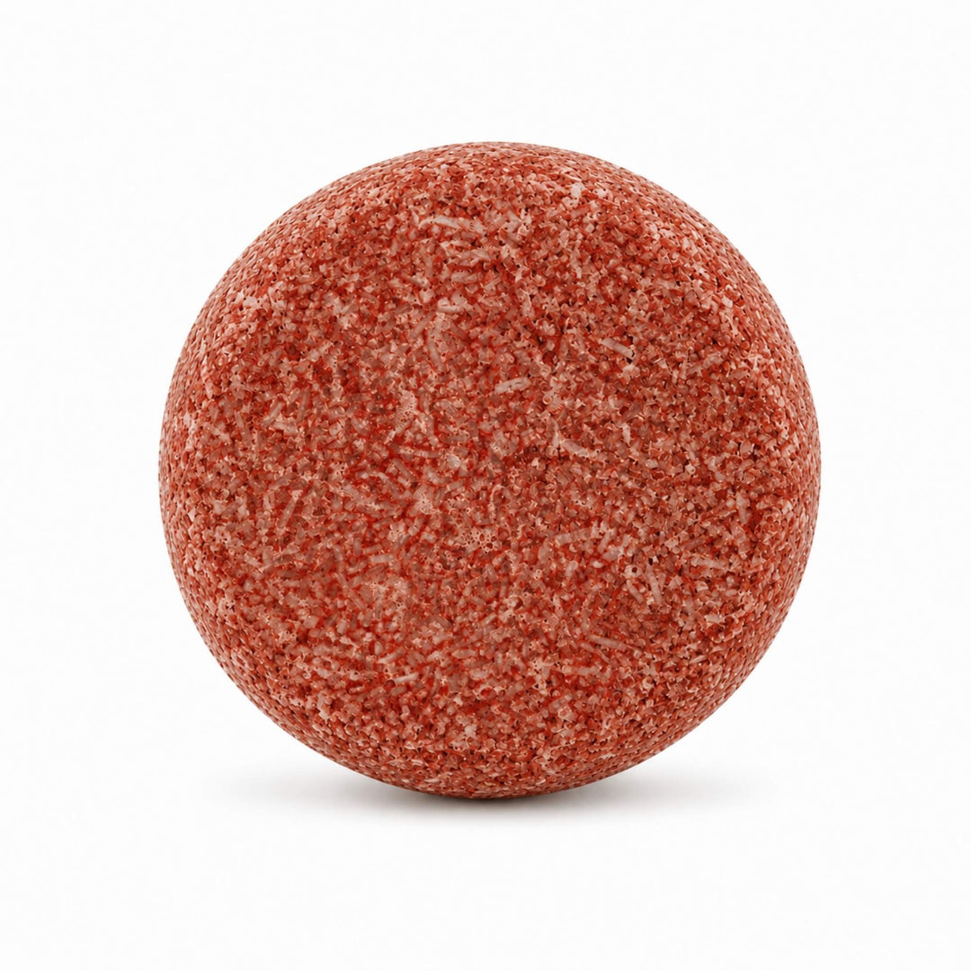 Dirty Bee Almond Coconut Shampoo Bar, a round textured terracotta red-orange shampoo bar, on a white background.
