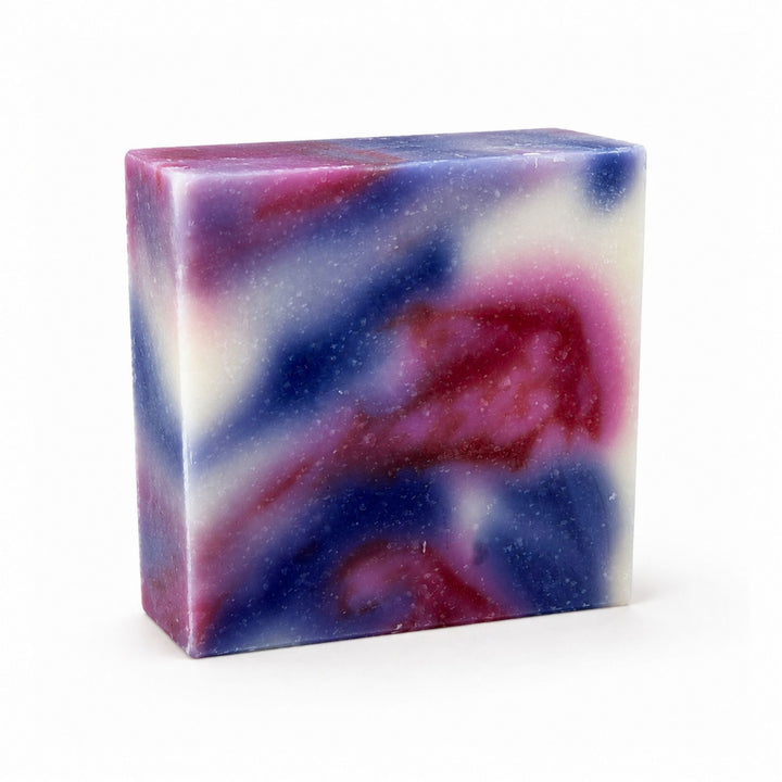 Dirty Bee Blasting Bomb Pop Soap Bar, a square bar with a marbled swirl of blue, purple, pink, and white with glittery flecks, on a white background.