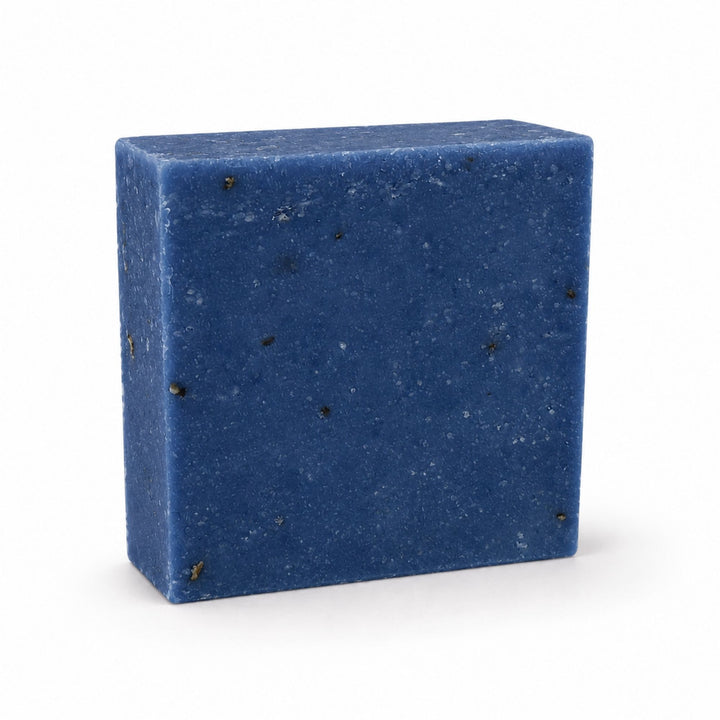 Dirty Bee Blueberry Muffin Soap Bar, a square deep blue soap bar with small dark flecks, on a white background.
