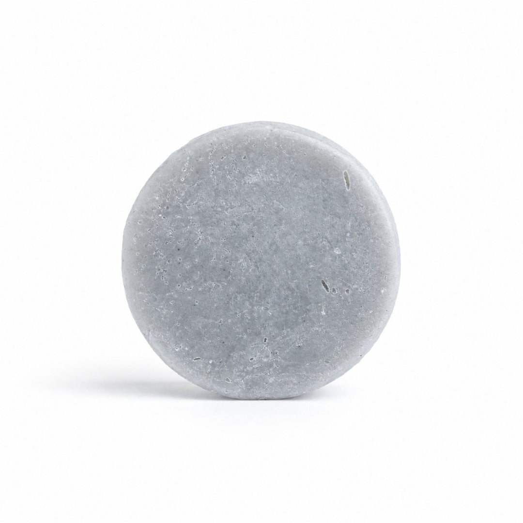 Dirty Bee Karma Conditioner Bar, a round gray stone-textured bar on a clean white background.