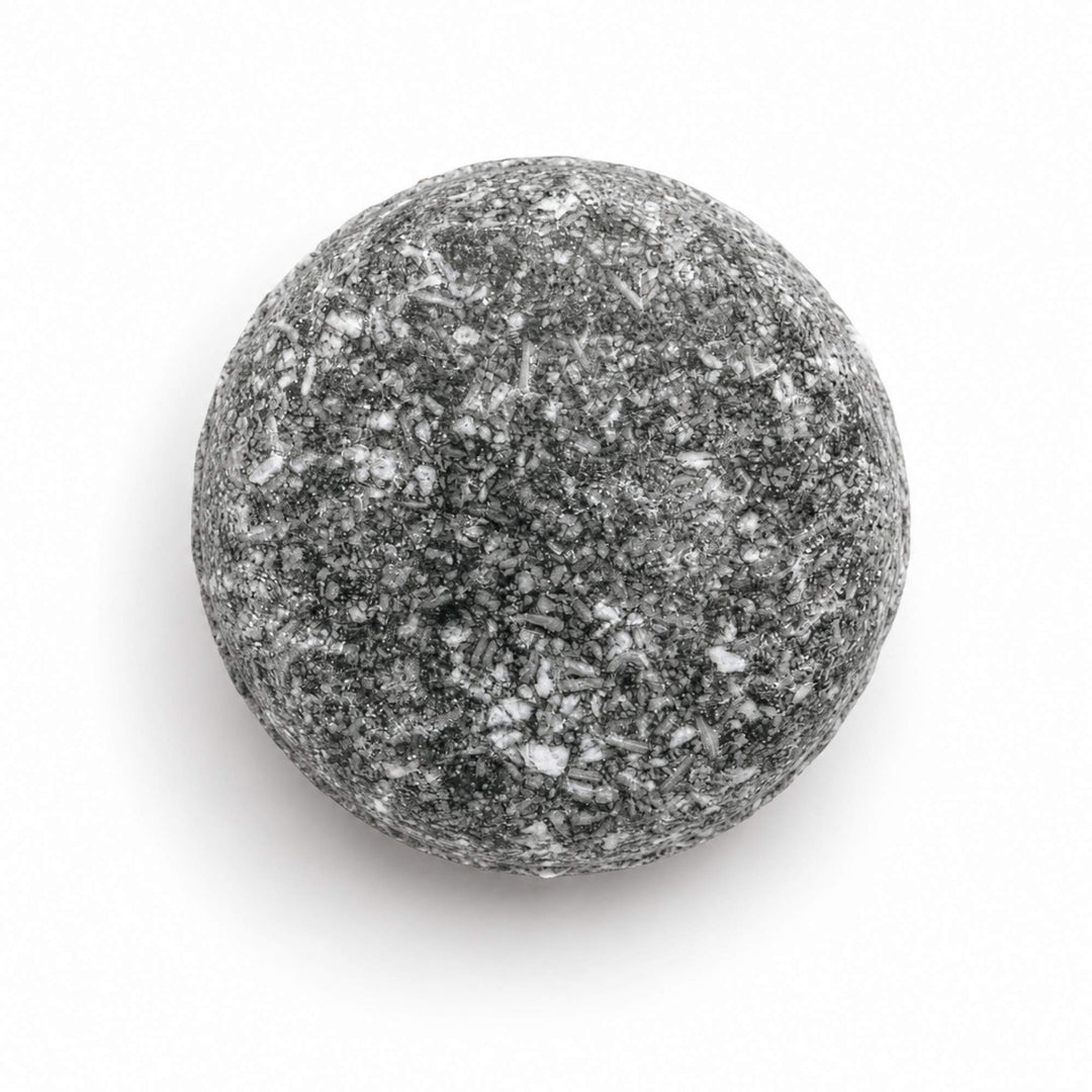 Dirty Bee Karma Shampoo Bar, a round gray speckled shampoo bar, on a white background.