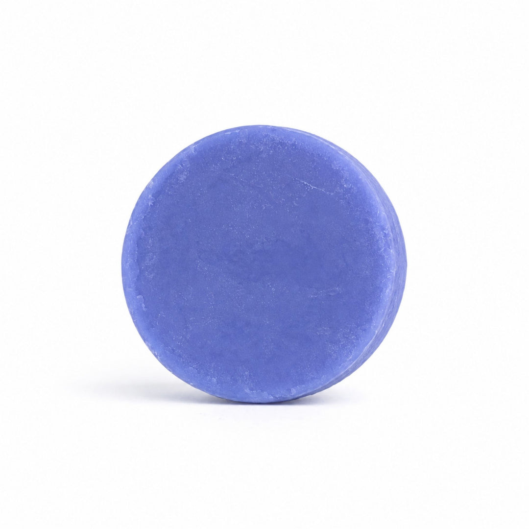 Dirty Bee Lavender Vanilla Conditioner Bar, a round periwinkle-blue solid bar on a clean white background.