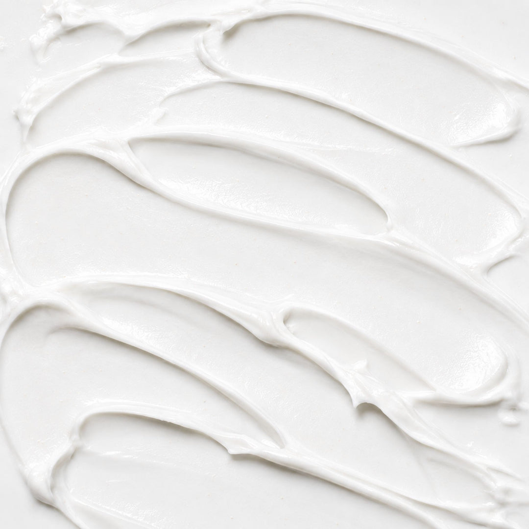 White lotion texture with smooth, creamy swirls and a soft glossy finish.