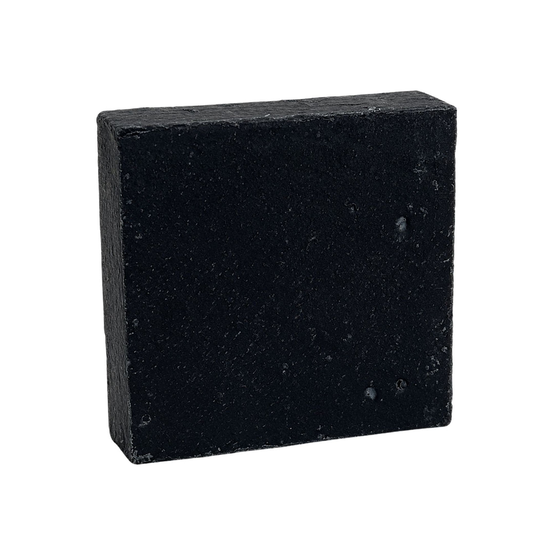 Midnight Detox charcoal soap bar with a deep black color and textured handmade surface on a white background.