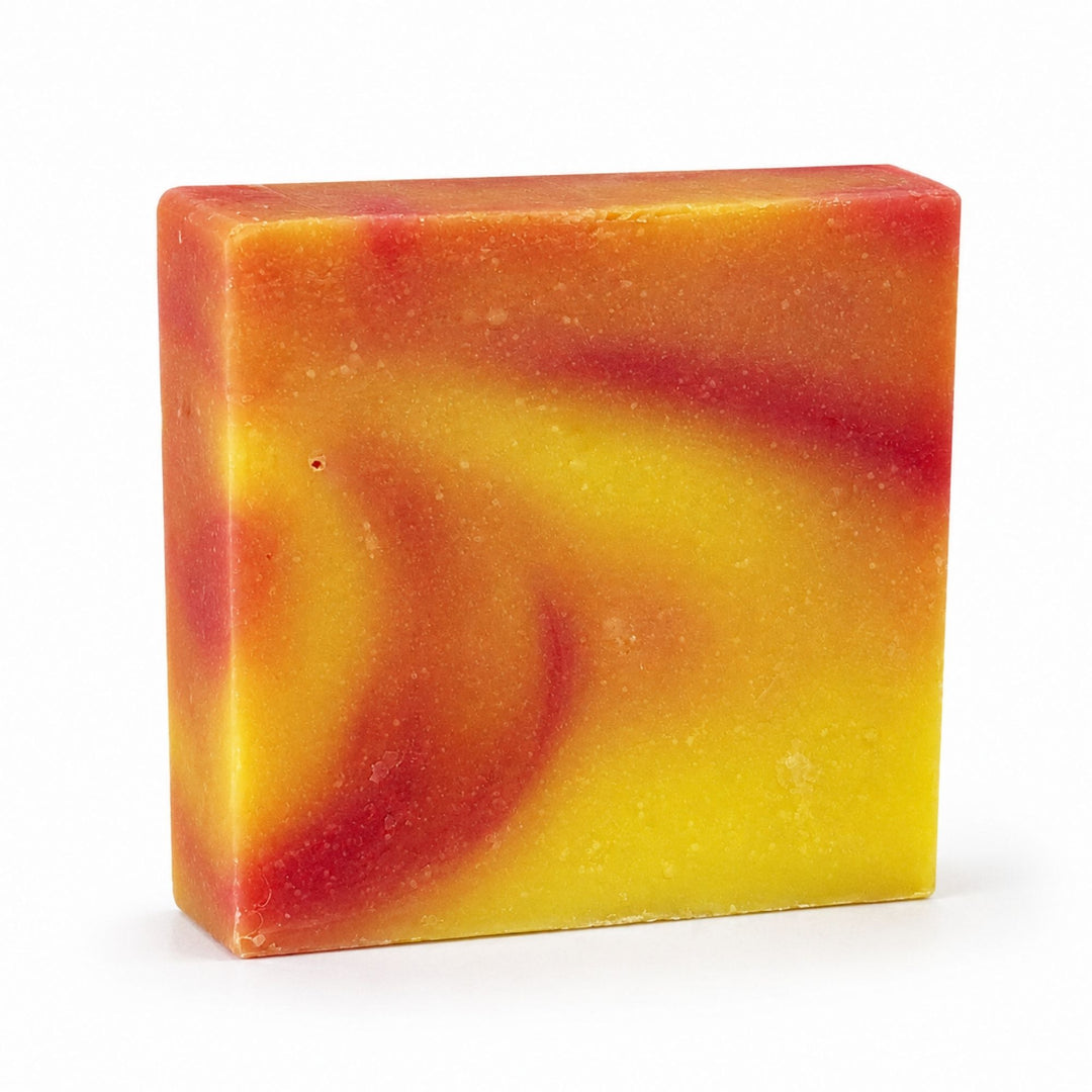 Dirty Bee Monkey Farts Soap Bar, a square bar with a marbled swirl of yellow, orange, and red, on a white background.