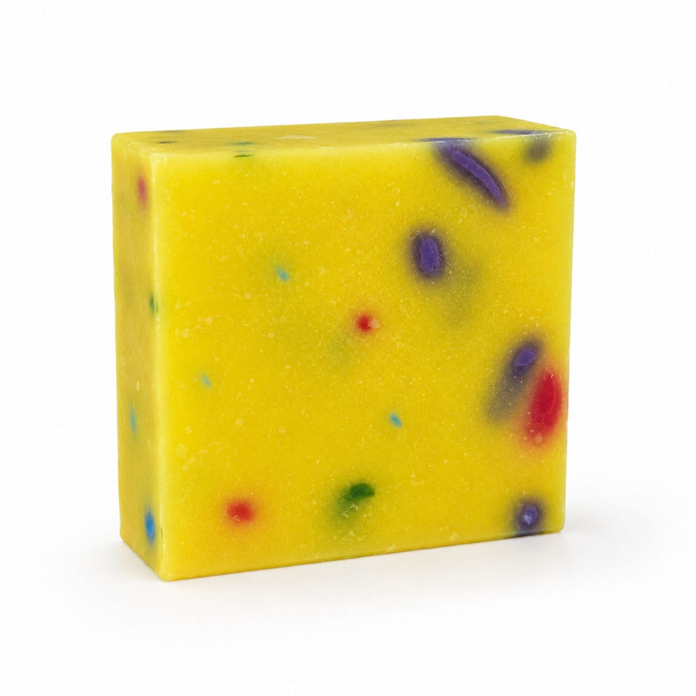 Dirty Bee Party Time Soap Bar, a square yellow soap bar with embedded multicolored flecks and swirls, on a white background.