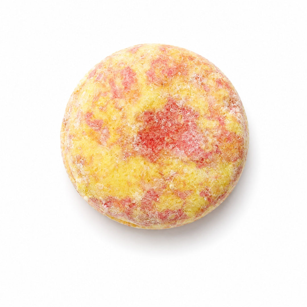 Dirty Bee Volcano Shampoo Bar, a round textured shampoo bar in yellow and red, on a white background.