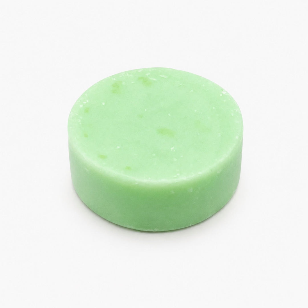 Centered product photo of a mint green coconut lime conditioner bar on a clean white background, shown as a smooth solid round bar with softly angled sides.