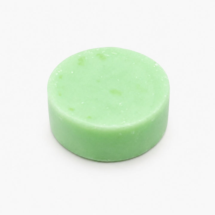Centered product photo of a mint green coconut lime conditioner bar on a clean white background, shown as a smooth solid round bar with softly angled sides.