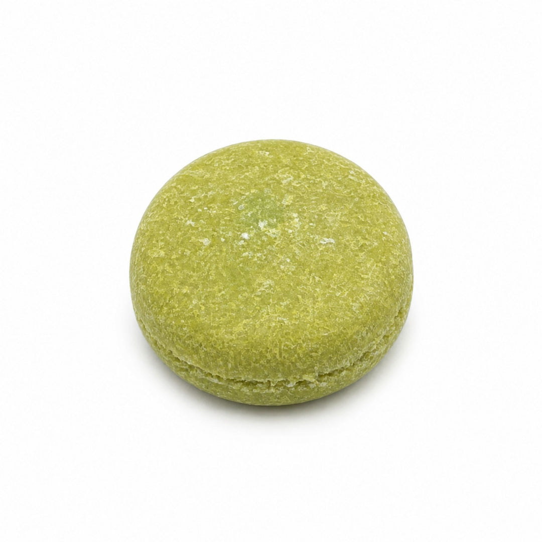 Dirty Bee Coconut Lime Shampoo Bar, a round green solid shampoo bar on a white background.