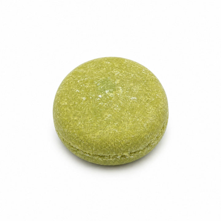 Dirty Bee Coconut Lime Shampoo Bar, a round green solid shampoo bar on a white background.