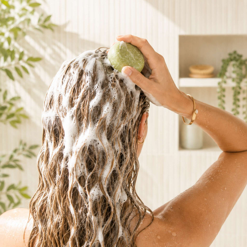 Dirty Bee Coconut Lime Shampoo Bar lathered through wet hair in a bright shower setting, showing the solid shampoo bar in use.